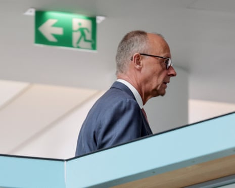 Friedrich Merz walks past a green exit sign at a CDU party meeting