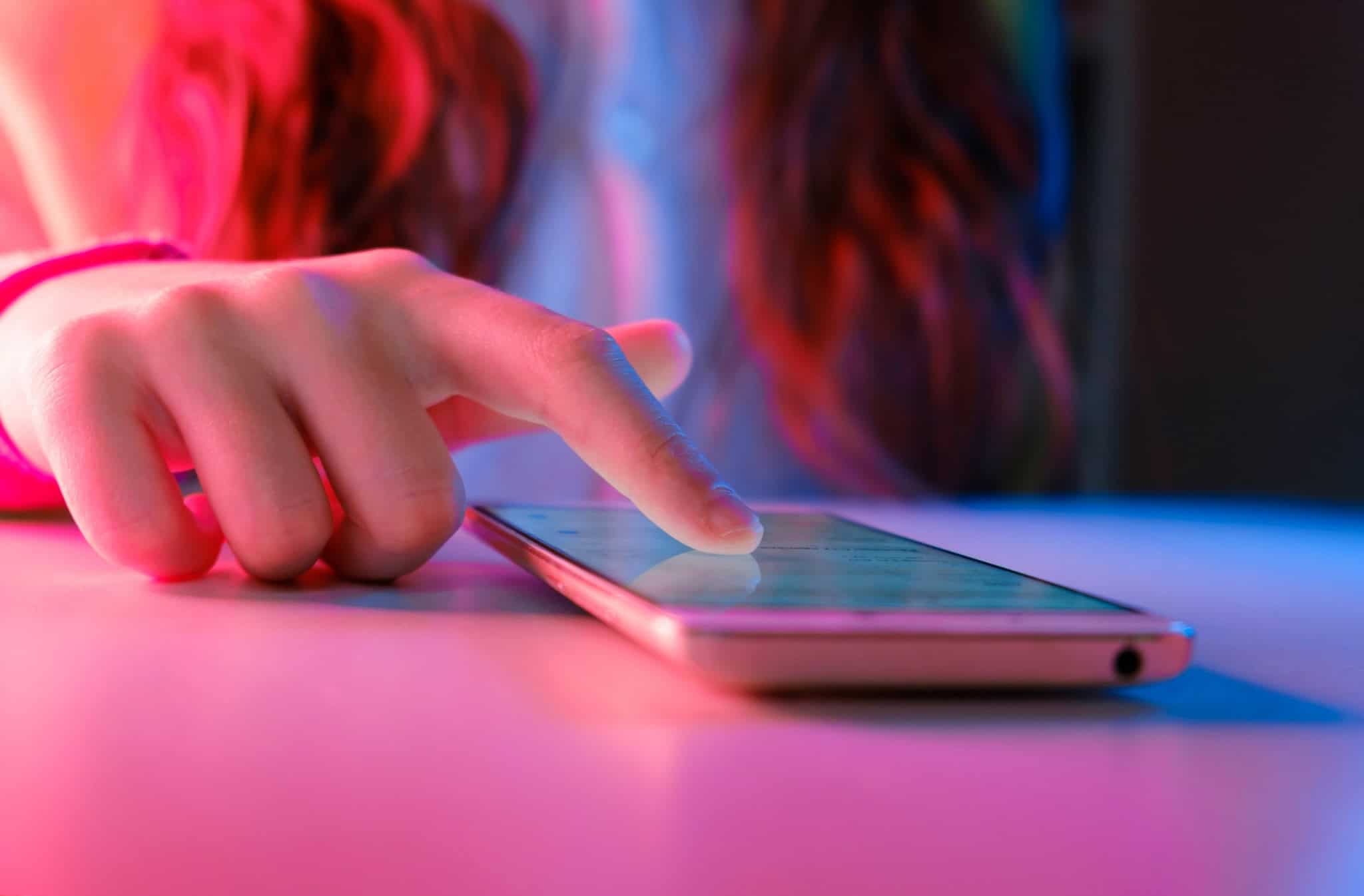 adolescente tocando na tela de um smartphone