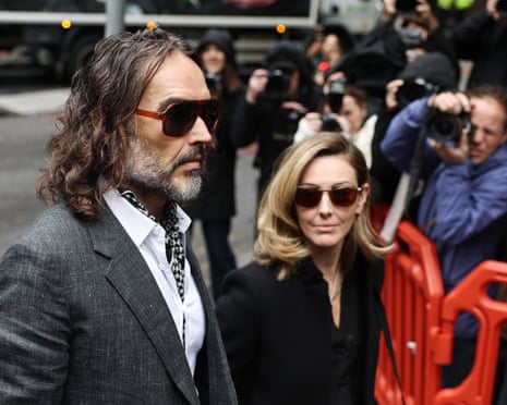 Russell Brand and his wife Laura arrive at court, photographers crowding behind them