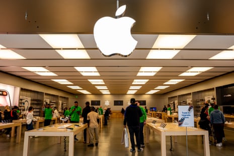 Shoppers browse tables beneath a large illuminated Apple logo inside the Towson store