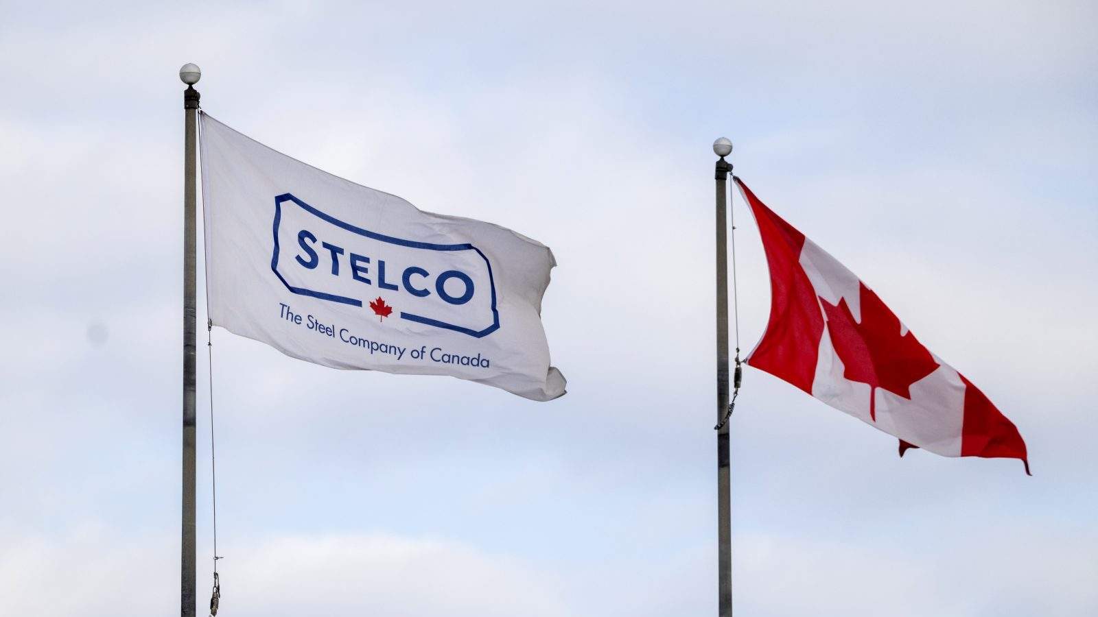 A Stelco flag flies beside a Canadian flag at the steel production facility in Hamilton, Ont., on Monday, February 10, 2025.