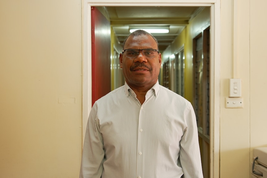 A doctor stands before a hallway in a hospital