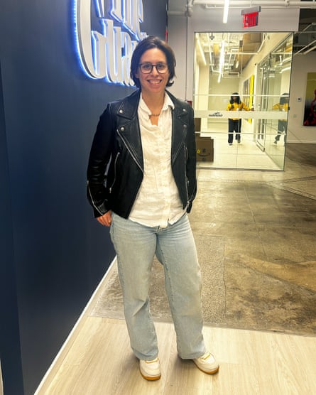 a woman in a black leather jacket, white button down and blue jeans