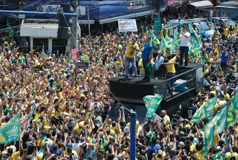 Já projetando dia de posse, Flávio promete entregar 'Brasil nas mãos de Deus' e Jair Bolsonaro colocando faixa presidencial