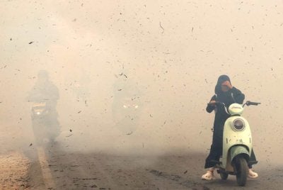 Penunggang motosikal meredah kepulan asap akibat kebakaran di Kampung Sungai Tabuk, Kabupaten Banjar, Kalimantan Selatan. Foto AFP